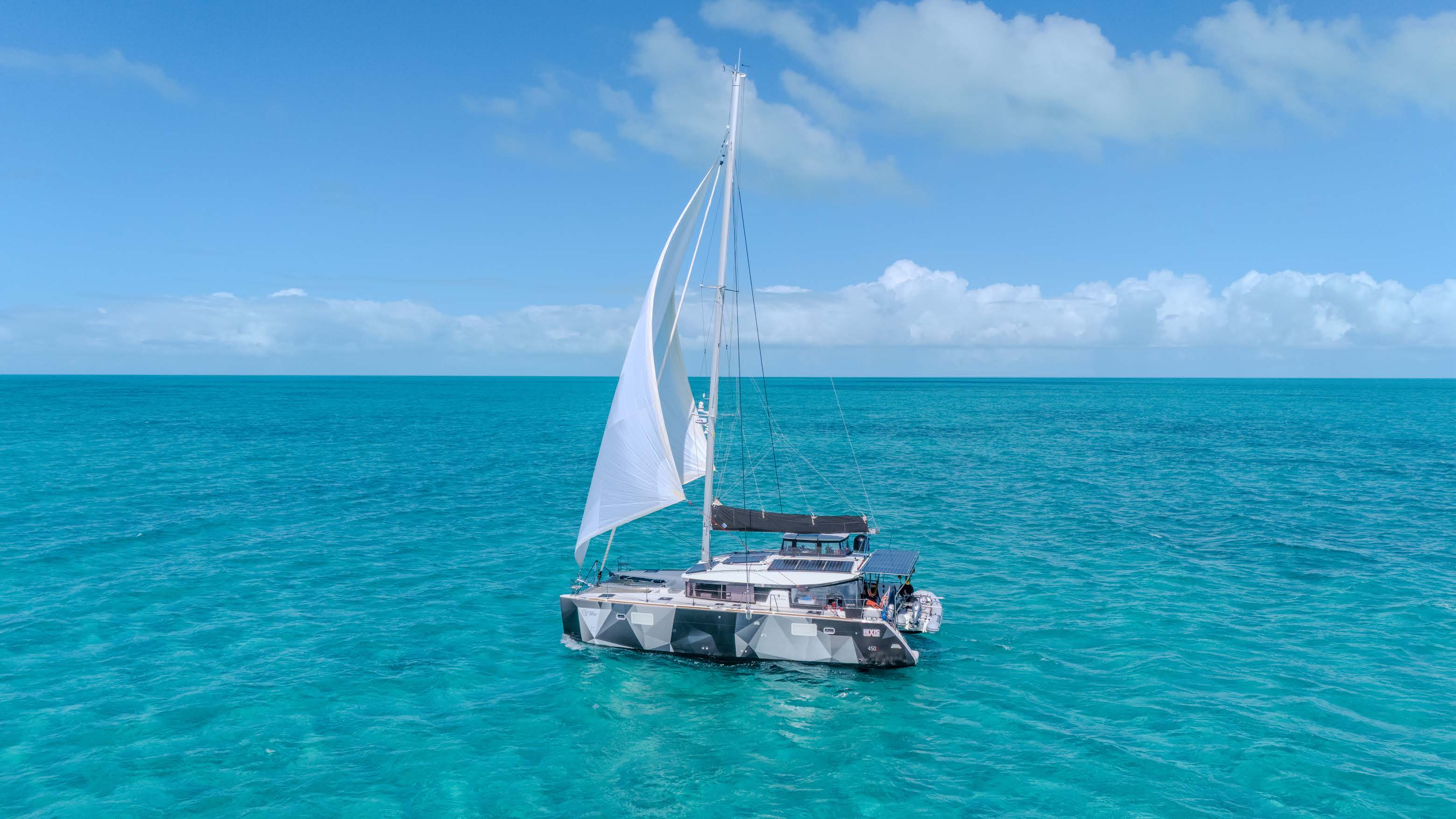 The catamaran Tellus under sail on turquoise water.